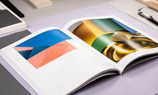 Brochure fotografica aperta su carta patinata lucida in uno studio grafico
