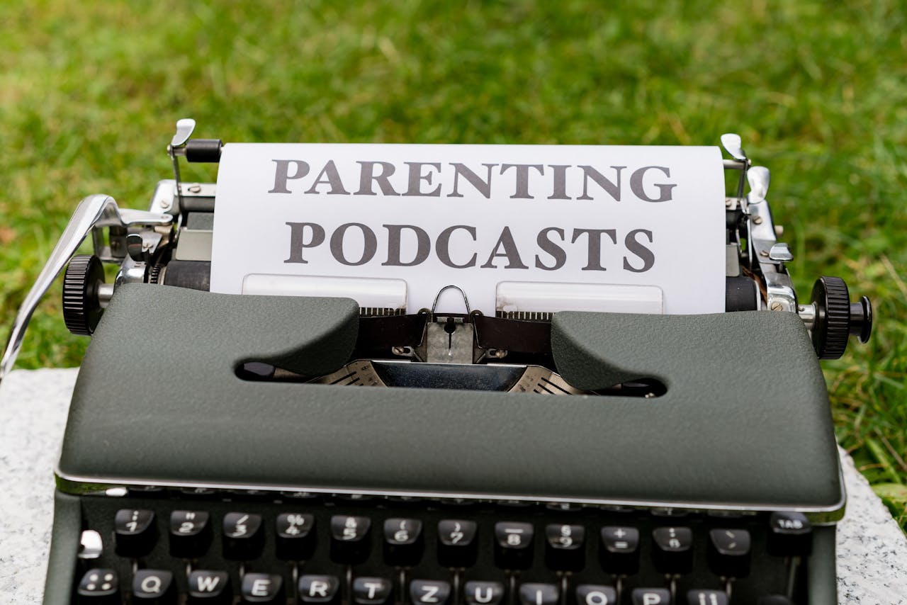 Close-up of an antique typewriter outdoors with focus on sheet labeled Parenting Podcasts.